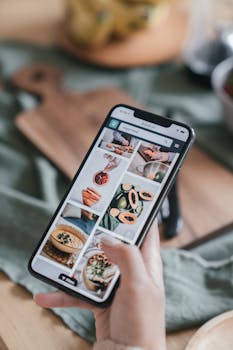 Close-up of a hand holding a smartphone browsing food recipe images.
