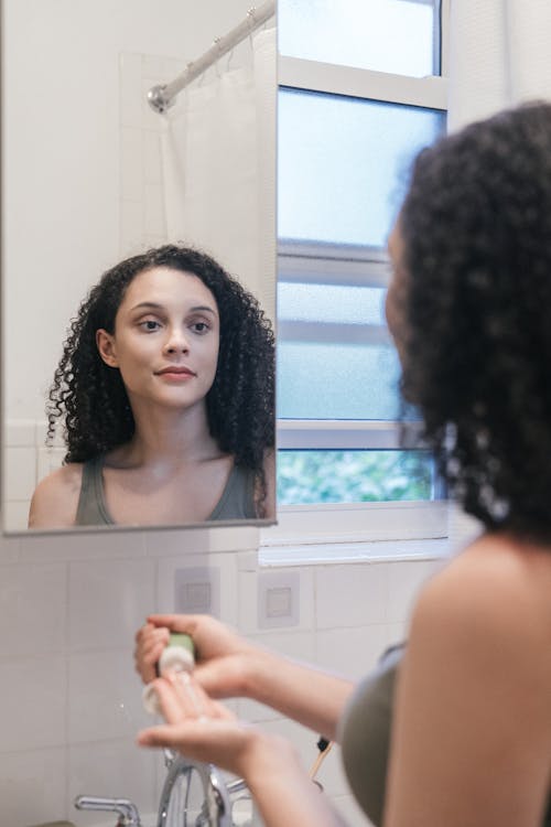 Woman in Tank Top Looking at a Mirror