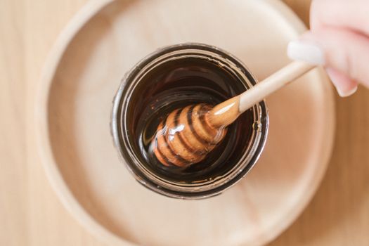 A honey dipper resting in a jar of golden honey