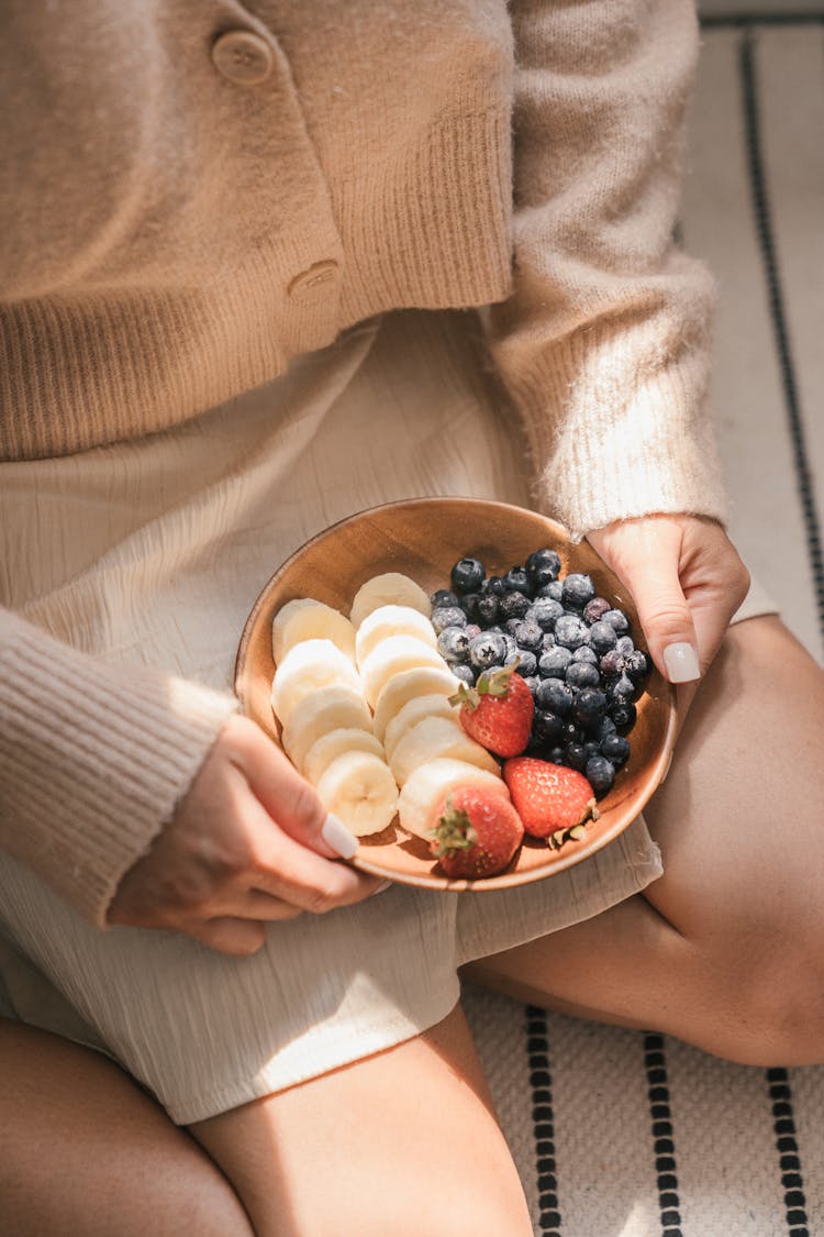 Woman Sitting While Holding A Bowl Of Mixed Fruits