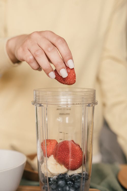 Woman's Hand Placing Strawberries in a Clear Container