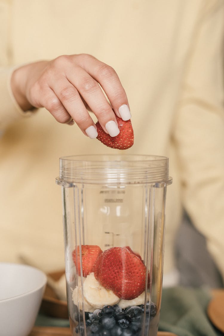 Woman's Hand Placing Strawberries In A Clear Container