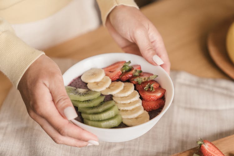 Person Holding A Bowl Of Sliced Mixed Fruits