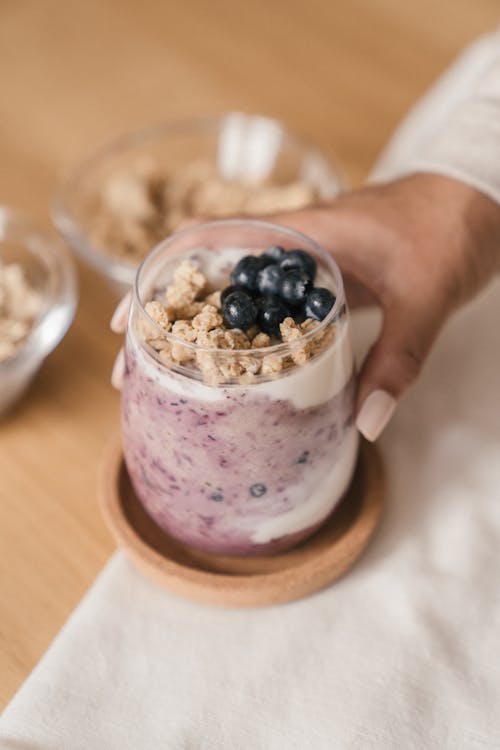 Person's Hand Holding a Blueberry Smoothie with Toppings