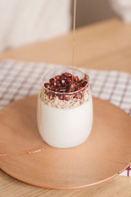 Free Creamy yogurt topped with fresh pomegranate seeds and oat flakes drizzled with honey. Stock Photo