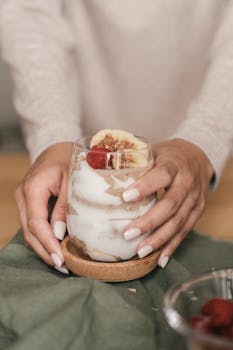Close-up of a fresh homemade fruit shake in glass held by a person.