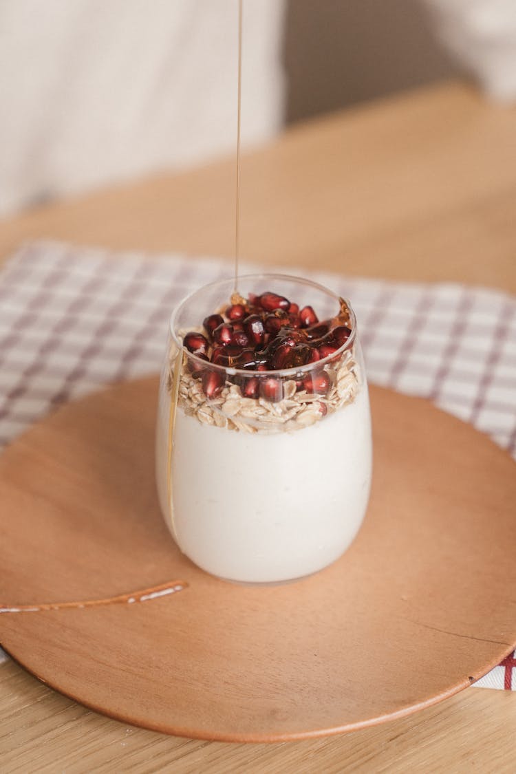 Honey Dripping On A Glass Of Yogurt With Pomegranate Seeds