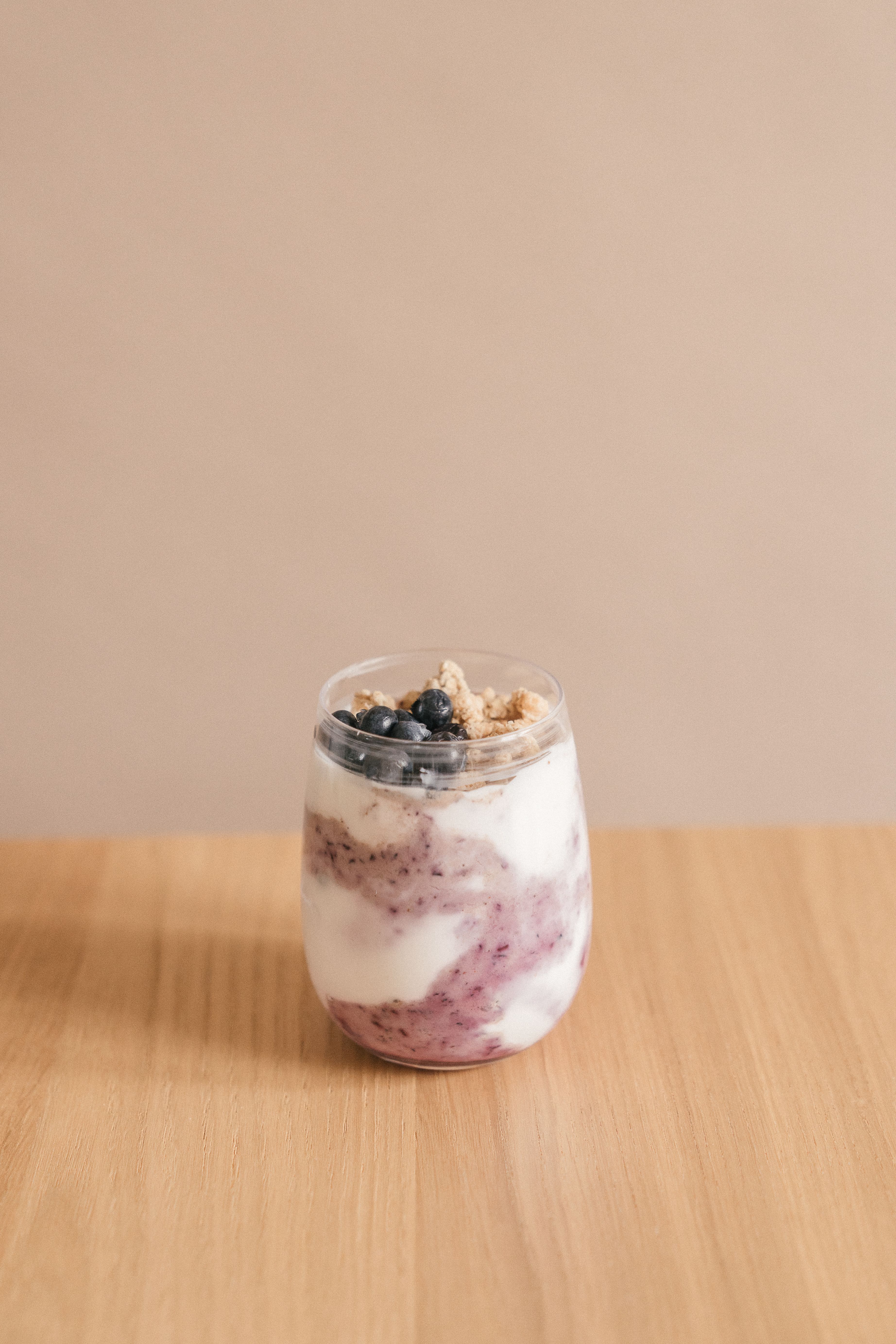 Creamy blueberry yogurt parfait with granola on a wooden table, perfect for healthy eating.