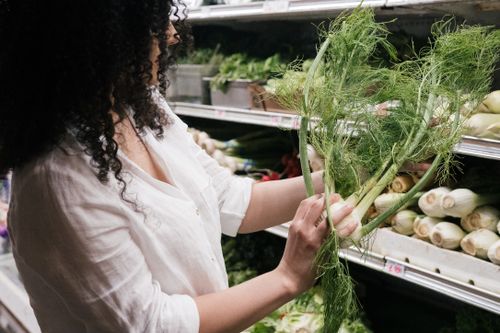 Free A woman in a white top choosing organic fennel in a grocery store produce section. Stock Photo