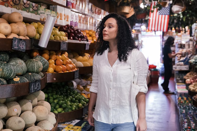 A Woman Looking For Vegetables And Fruits Inside The Market