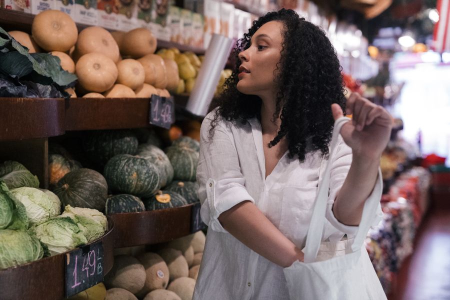 Woman holding eco bag choosing fresh vegetables at a local market.