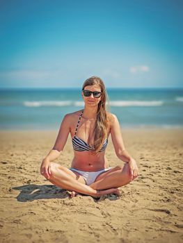 Relaxed woman meditating on a sunny beach in Rosiana, Spain, enjoying the summer vibes.
