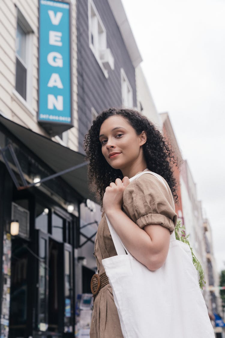 A Beautiful Curly-Haired Woman Carrying A Tote Bag