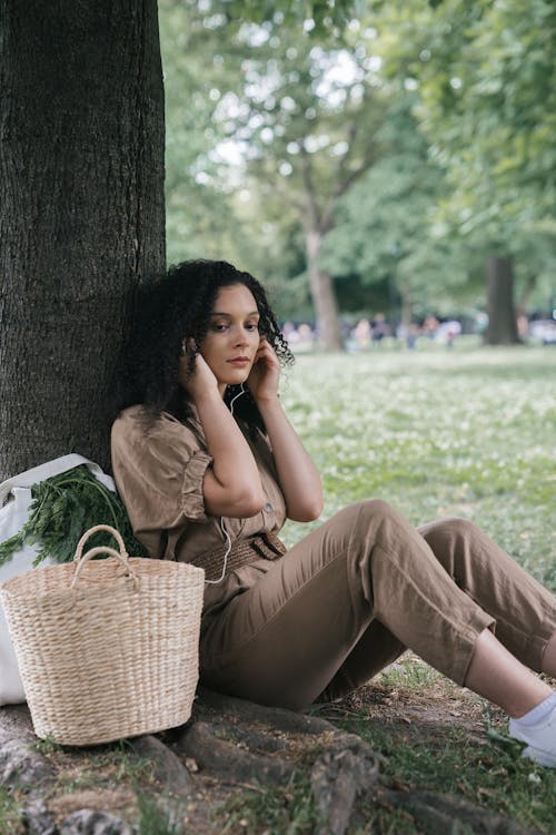 Free Woman Wearing Brown Jumpsuit Sitting Under a Tree Stock Photo