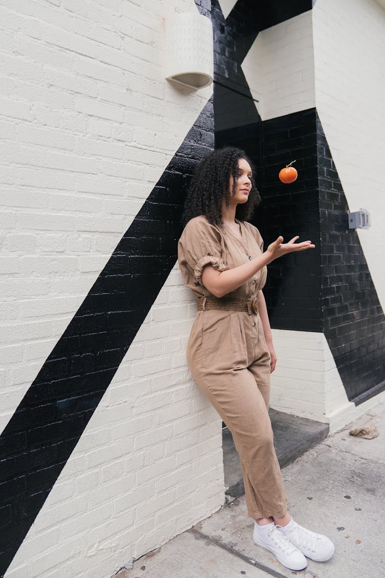 Woman In Jumpsuit Tossing A Fruit