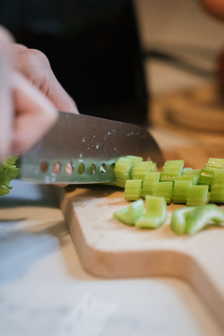 Person Chopping Celery On Wooden Chopping Board