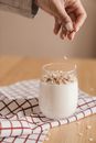 Person sprinkling Oats in a Glass of Smoothie