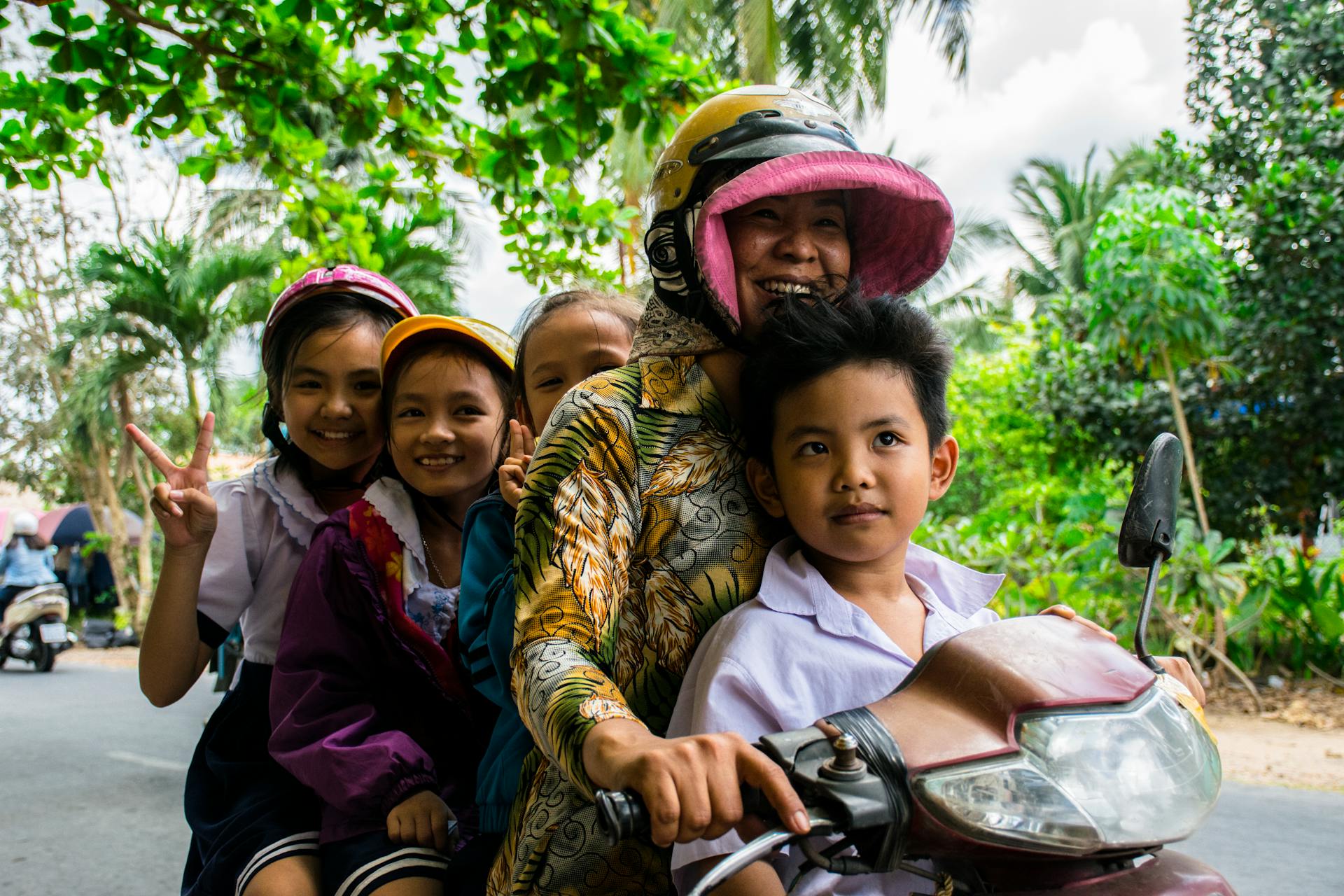 Group of smiling children on a motorcycle ride through Ho Chi Minh City, capturing happiness and innocence.