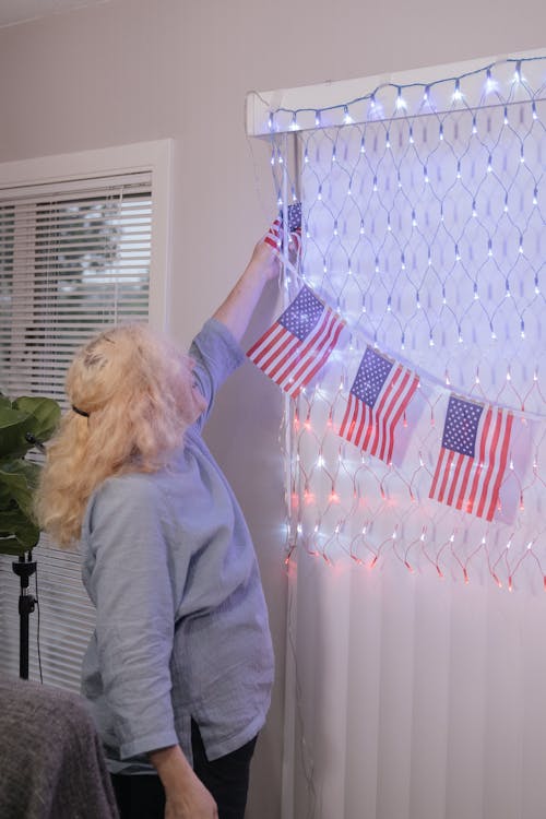 Free Elderly Person hanging American Flags at a Window  Stock Photo