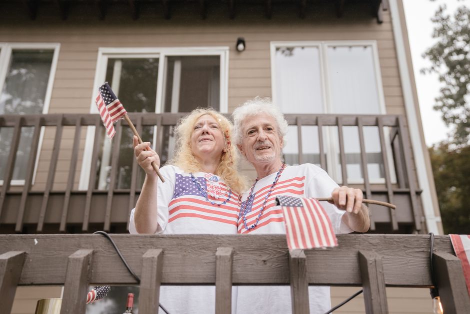 man standing front porch american flag