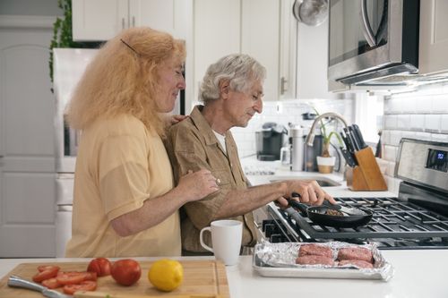 Free Senior couple enjoying quality time cooking together in a modern kitchen setting. Stock Photo