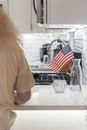 Person in Yellow Shirt Sitting Behind the Kitchen Counter with American Flag in a Glass Jar