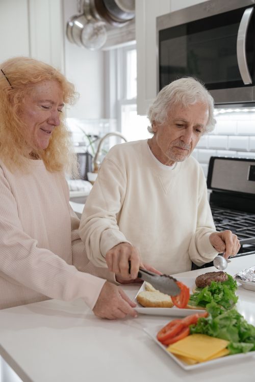 Free Elderly couple preparing burgers together in a contemporary kitchen setting. Stock Photo