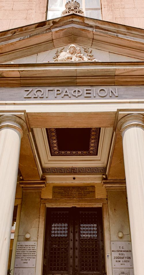 Free Elegant entrance of a classical Greek building with iconic columns and detailed architectural elements. Stock Photo
