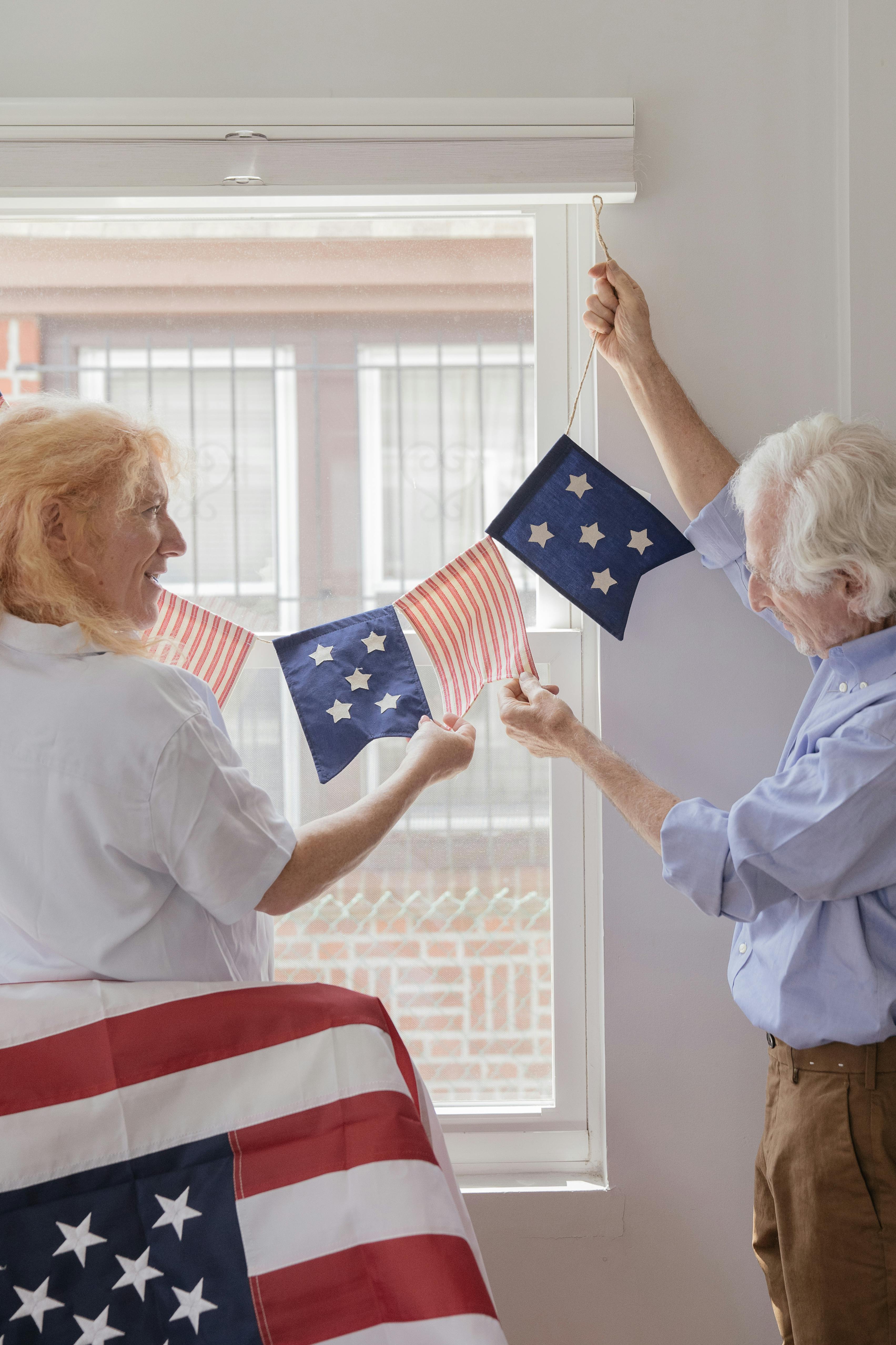 elderly couple hanging american flag by the window