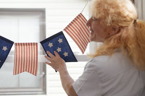 A Woman in White Shirt Hanging American Flag Banners 