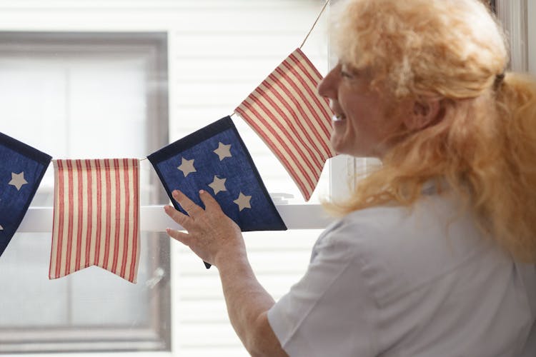 A Woman In White Shirt Hanging American Flag Banners 