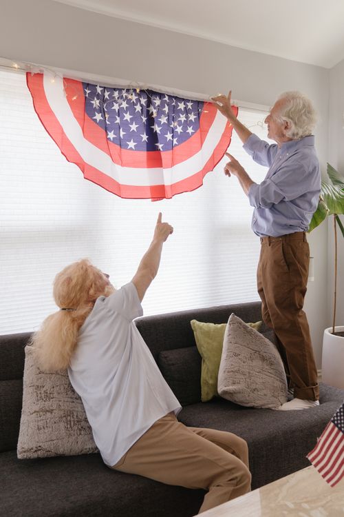 Free Senior couple sets up patriotic decor inside their home for 4th of July celebration. Stock Photo