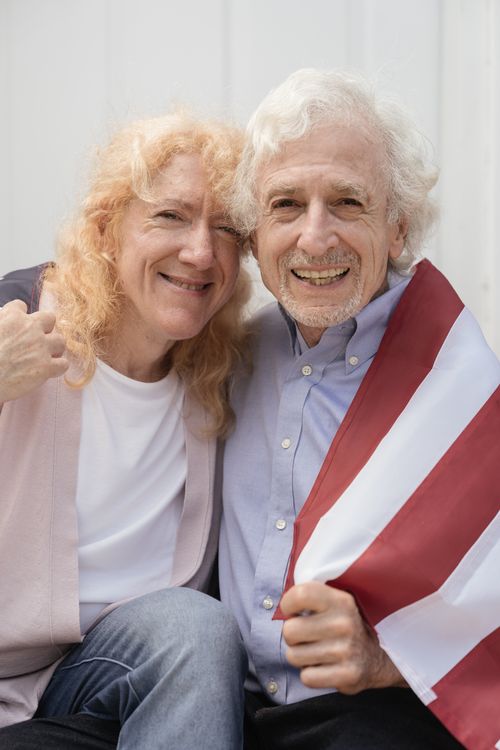 Free Joyful elderly couple embracing patriotism holding an American flag outdoors. Stock Photo