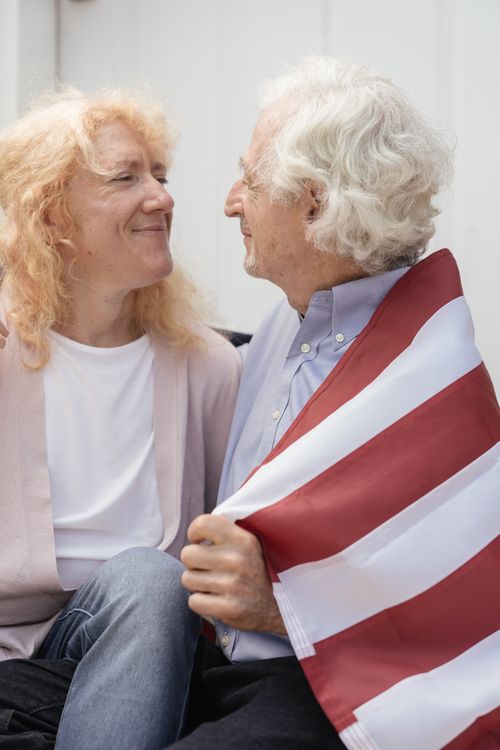 Free An elderly couple expressing love as they celebrate with a striped flag, emphasizing unity. Stock Photo