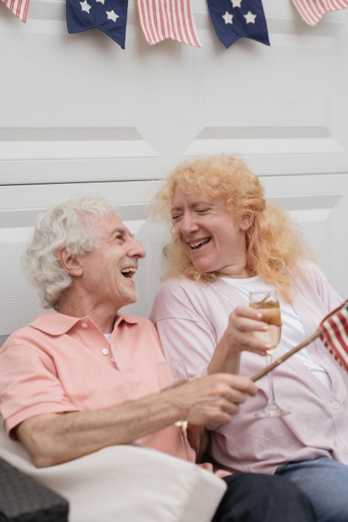 Free Lively senior couple enjoying Independence Day with laughter and champagne. Stock Photo