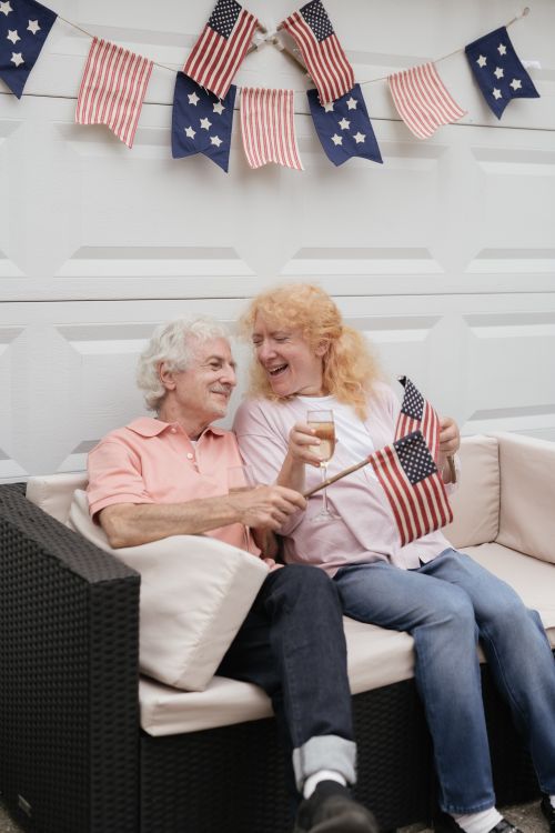 Free Senior couple celebrating Independence Day with American flags and a joyful smile. Stock Photo