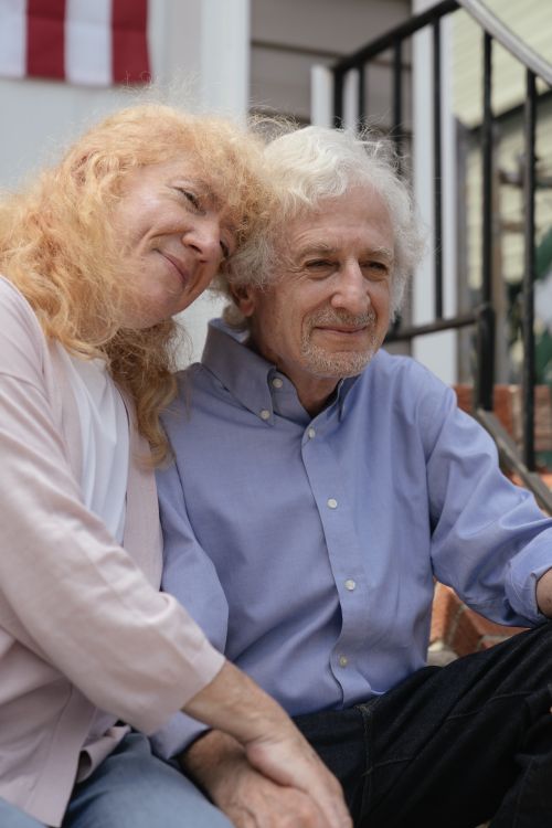 Free An affectionate elderly couple embracing while seated outdoors, capturing their closeness and happiness. Stock Photo