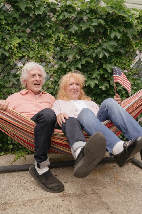 Free Joyful senior couple enjoying a relaxing moment together outdoors in a colorful hammock. Stock Photo