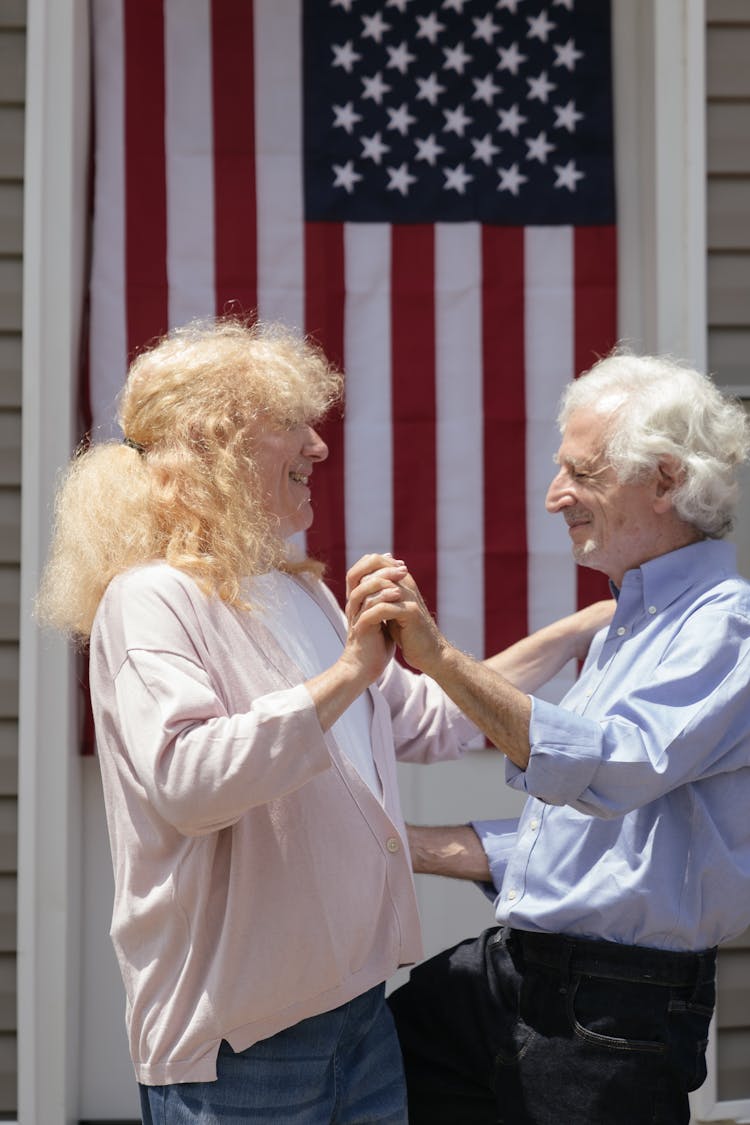 A Couple Dancing With An American Flag Hanging On Background