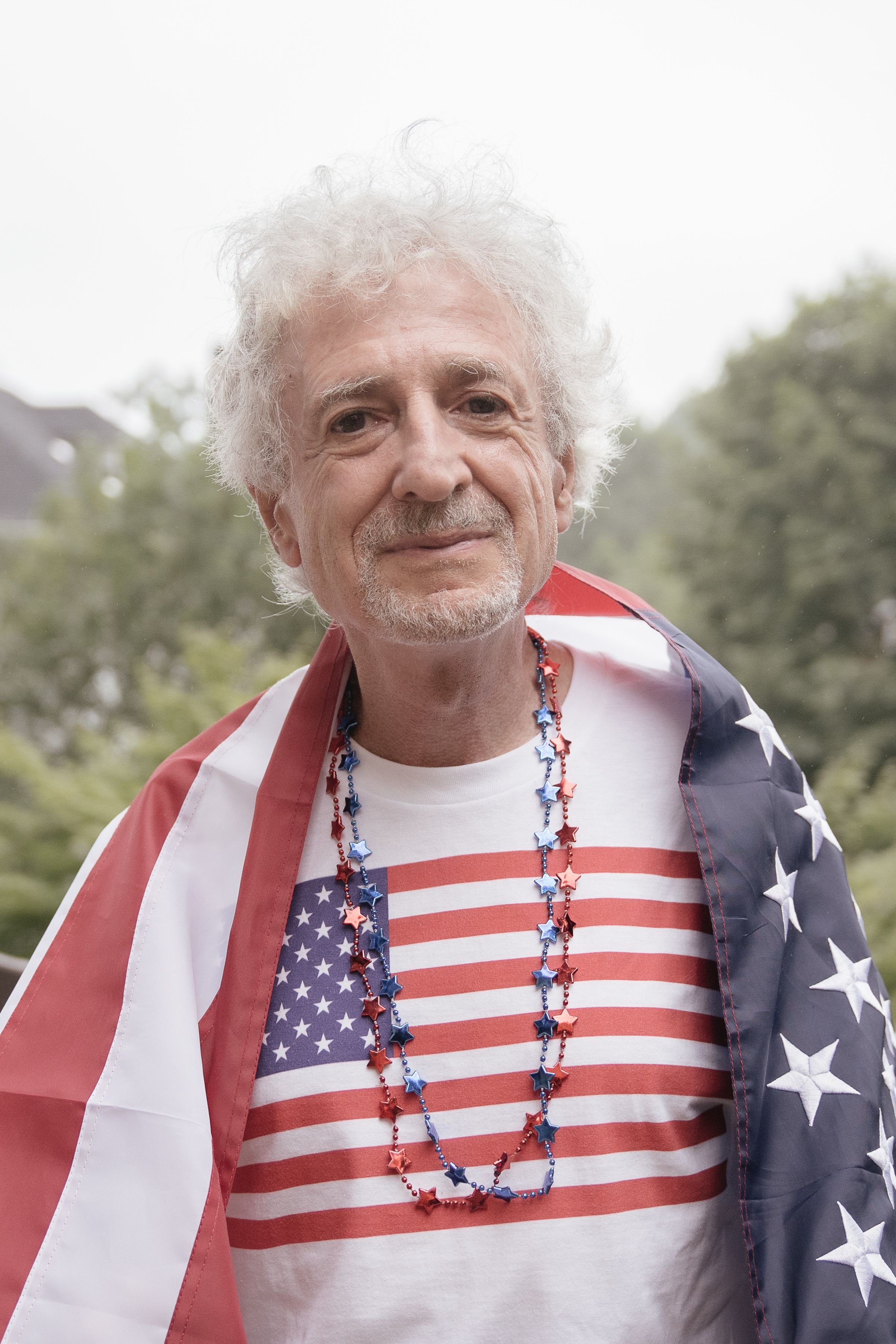 Senior man draped in an American flag, celebrating Independence Day with pride.