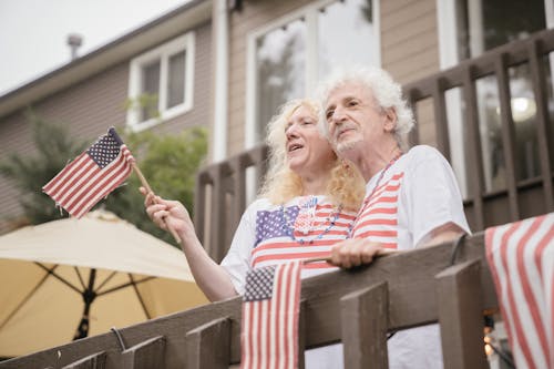 An Elderly Couple Holding US Flags