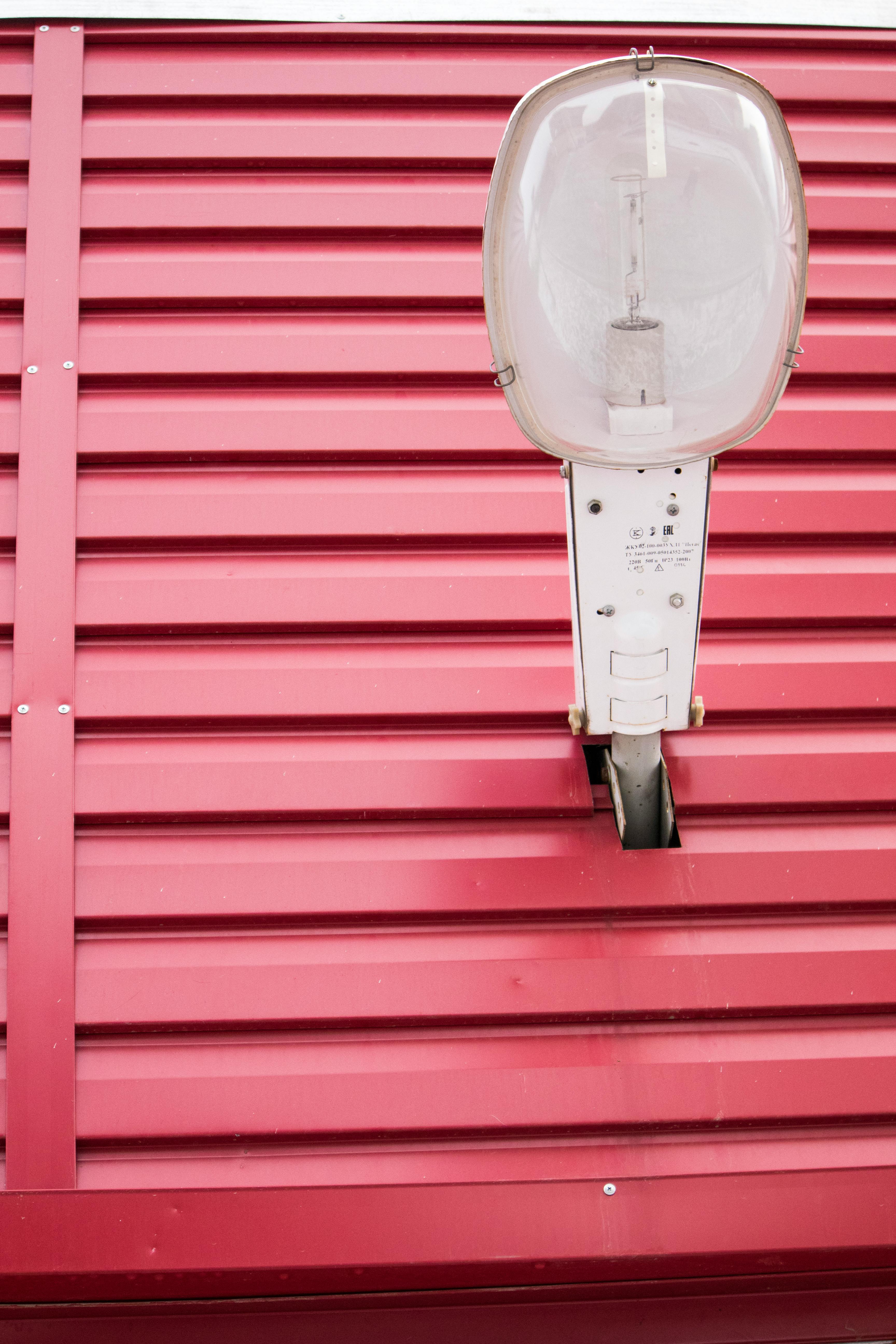 复古路灯与红色波纹金属墙的特写，凸显了工业设计