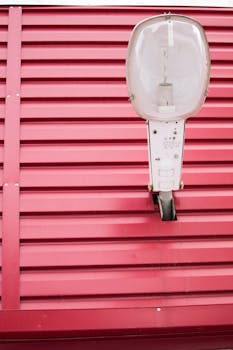 复古路灯与红色波纹金属墙的特写，凸显了工业设计