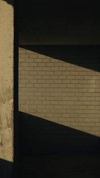 Dramatic shadows on a brick wall creating a geometric pattern in an urban setting.