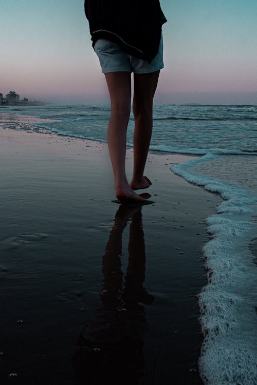 Photo of a Person Walking on the Ocean Shore