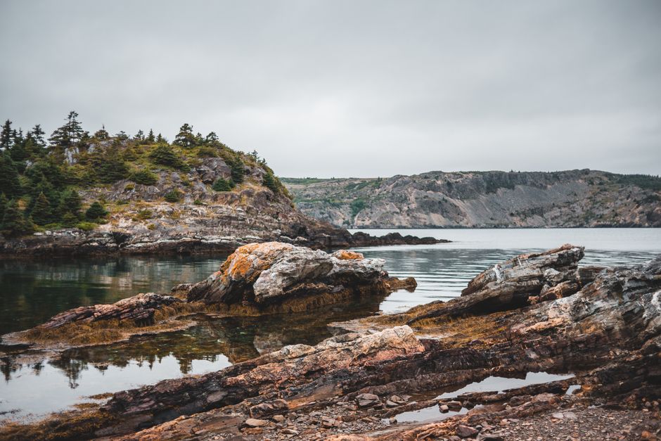 Explore this stunning rocky coastline with lush greenery and serene waters.