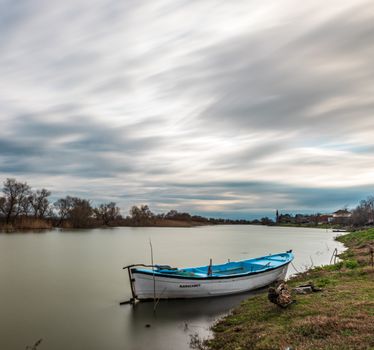 White and Blue Boat Docked on Riverbank