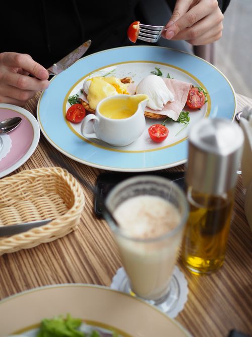 Free Close-up of a delicious brunch featuring eggs benedict, cherry tomatoes, and freshly squeezed juice in a cozy setting. Stock Photo