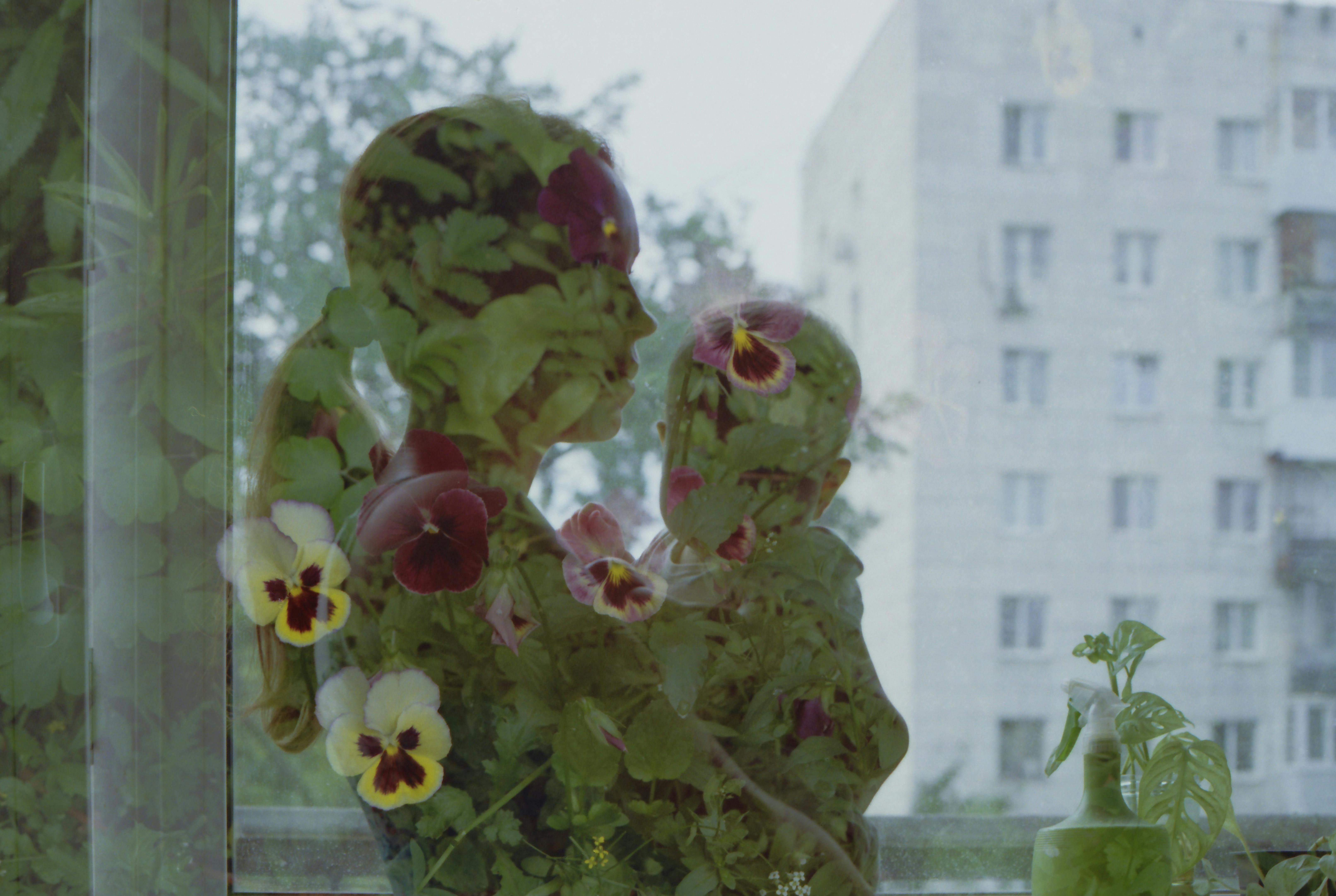 Artistic double exposure of mother holding child with floral overlay.