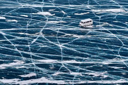 Free A van driving across the icy surface of Lake Baikal with intricate ice patterns. Stock Photo